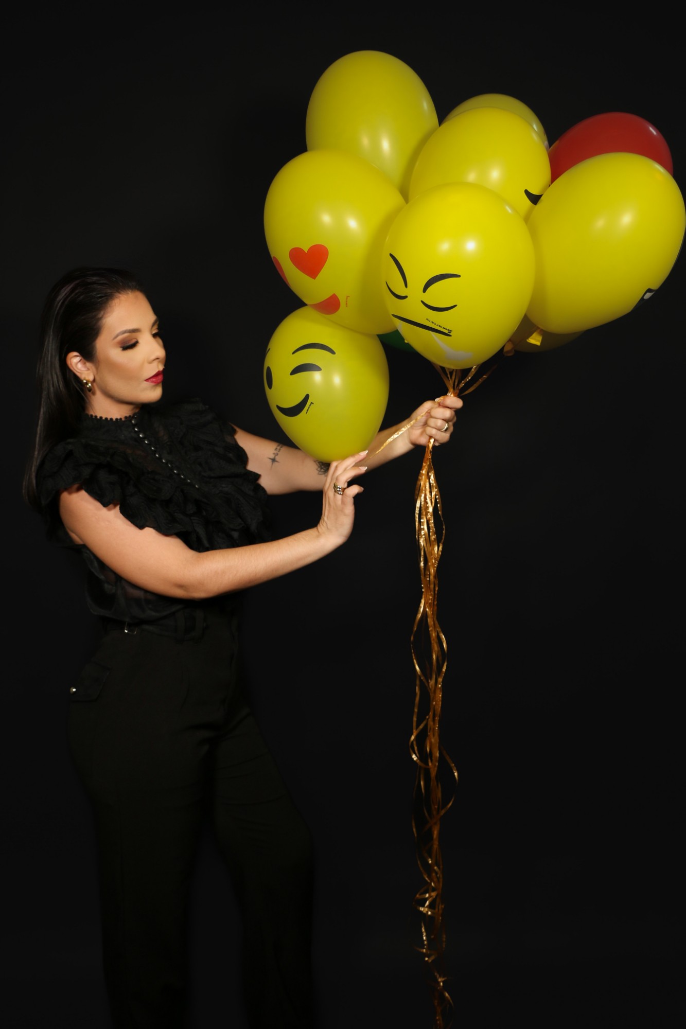 Jéssica Andrapa segurando balões amarelos com rostos de emoji