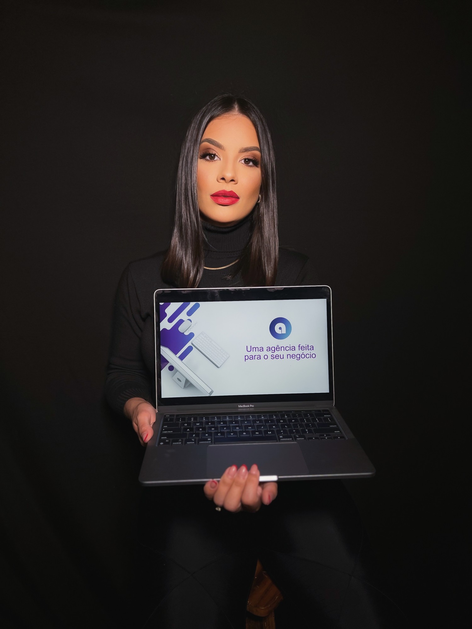 Jéssica Andrapa segurando um notebook com um site da Andrapa na tela